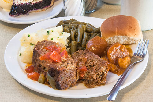 dinner plate of meatloaf with roll, vegetables, pie and coffee