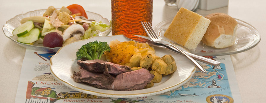 dinner plate with roast beef and vegetables, salad, rolls and tea