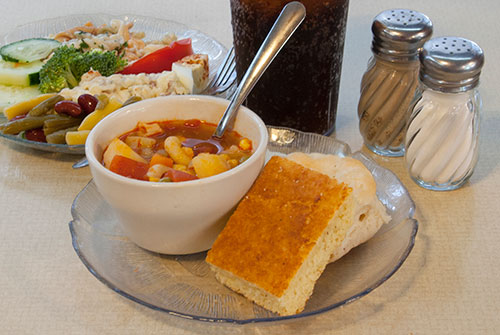 homemade cup of soup with cornbread, salad and drink